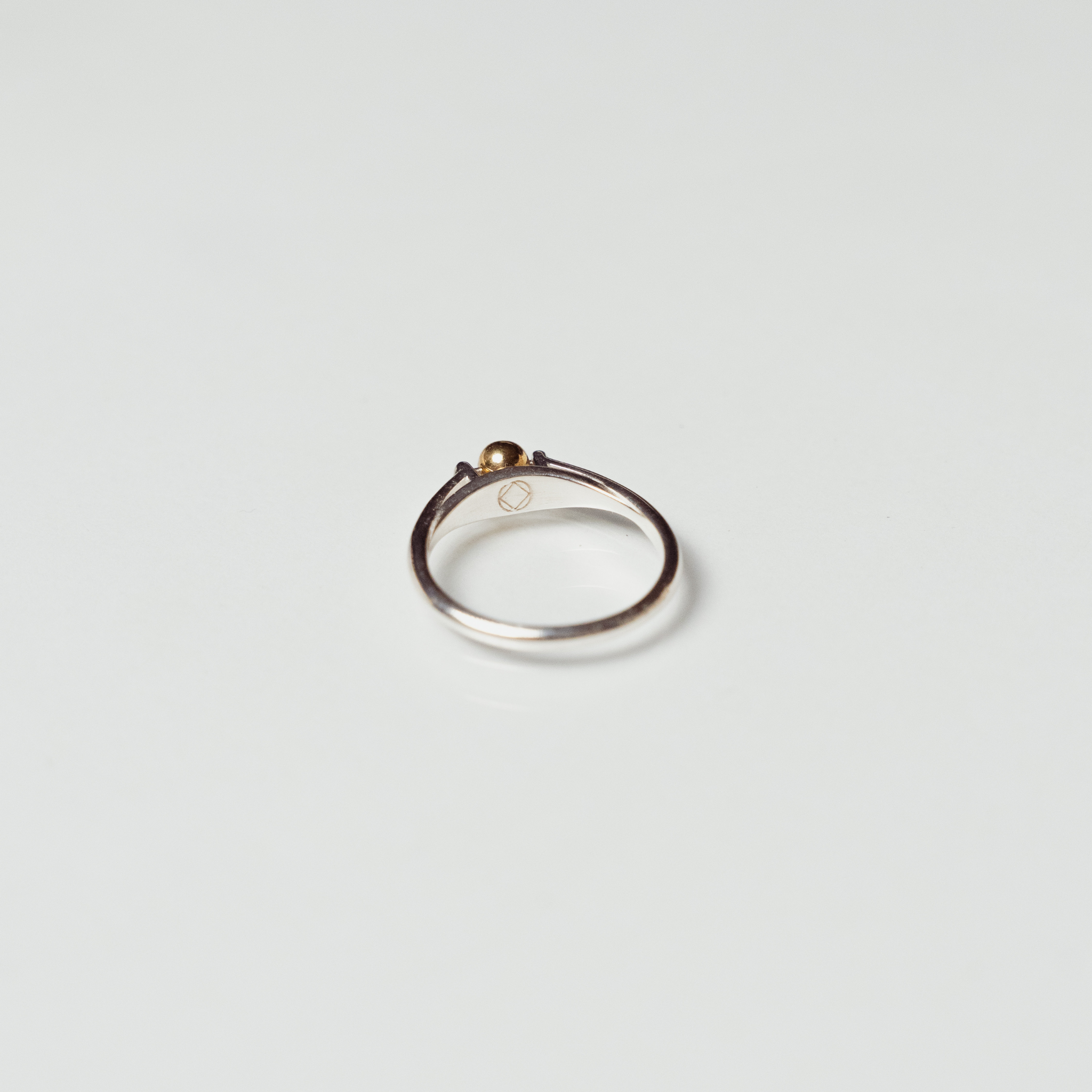 The India ring anxiety ring with silver band and mounted bronze ball on white background