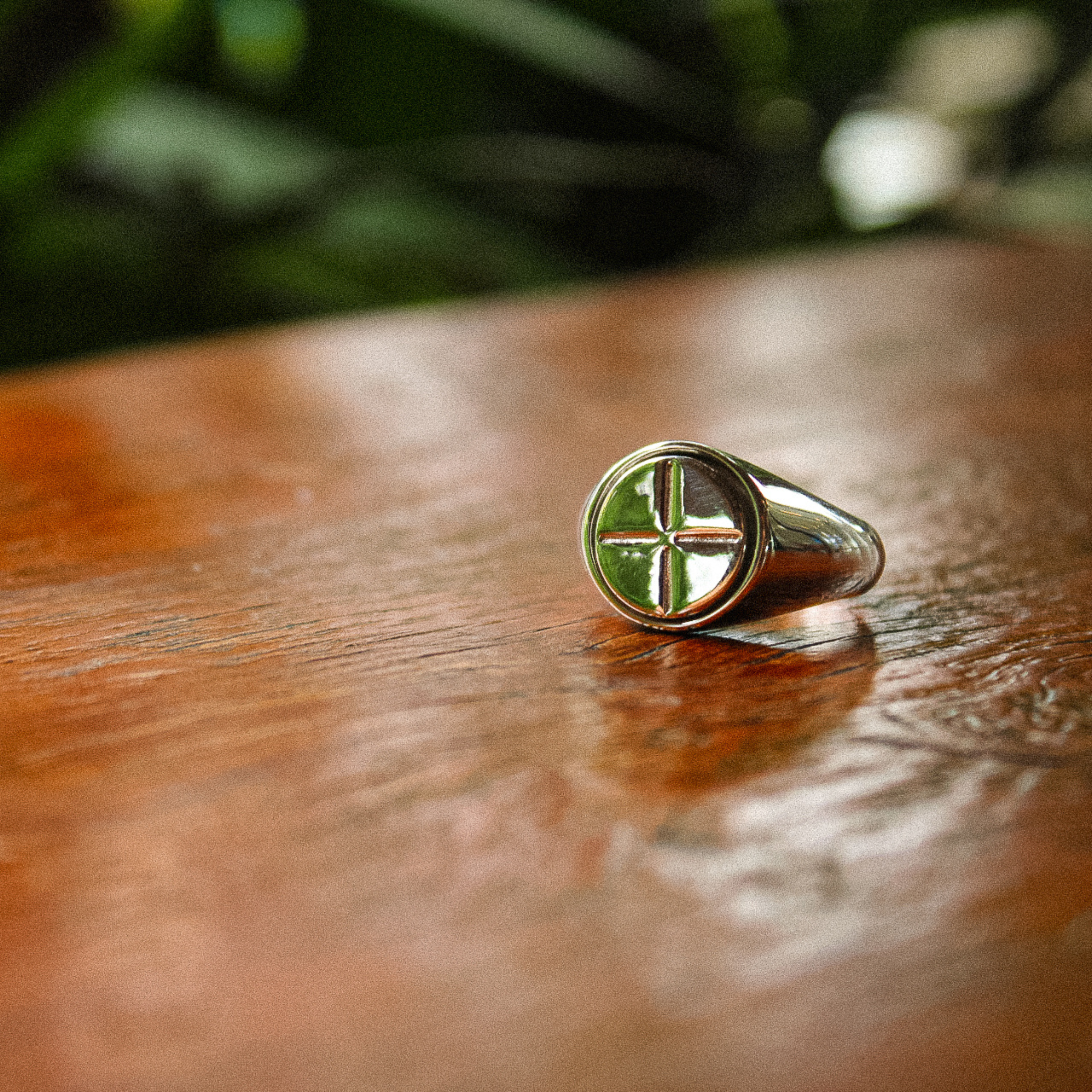 The Kai anxiety ring resting on a wooden table with green trees in background