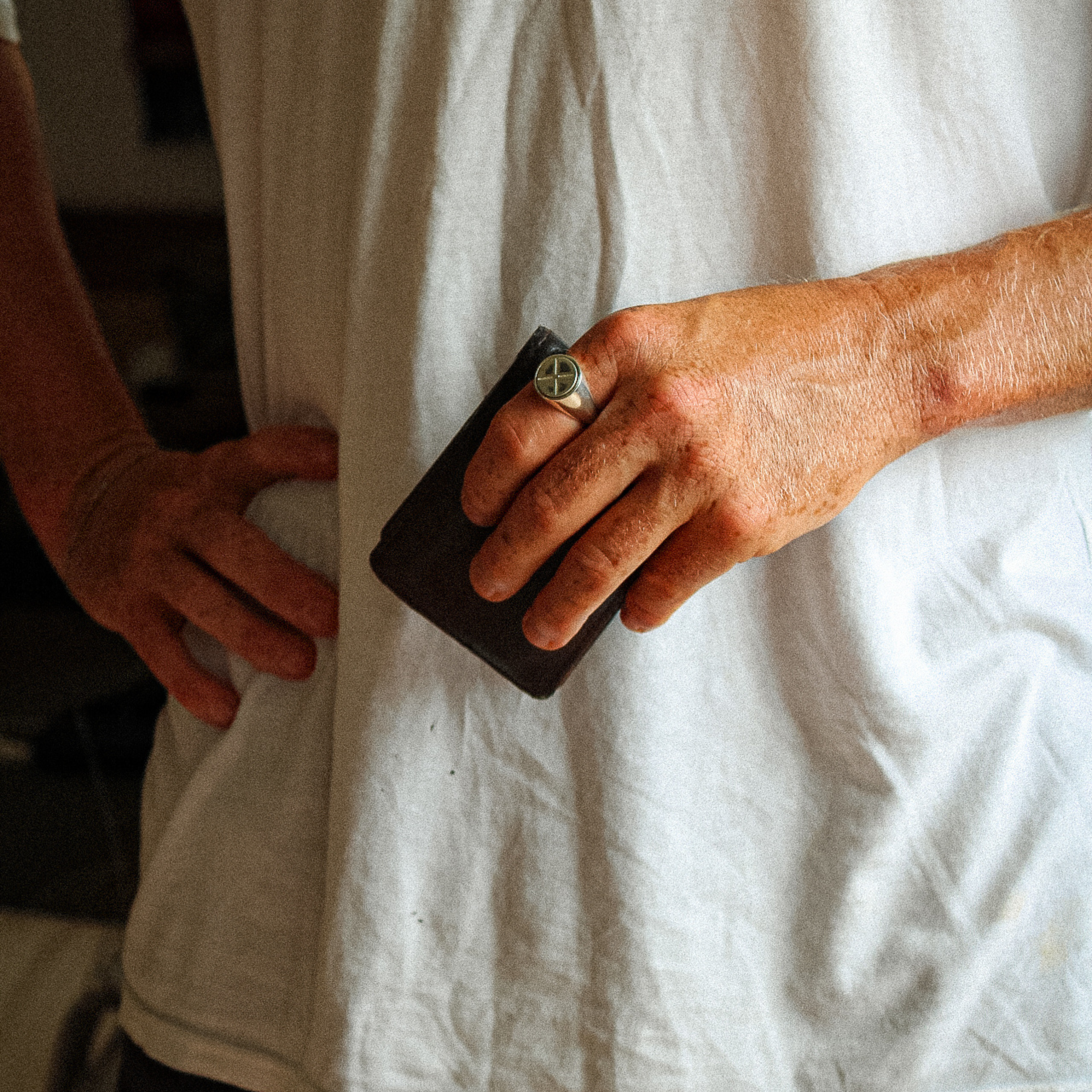 A man holding his brown wallet and wearing the Kai Anxiety Ring