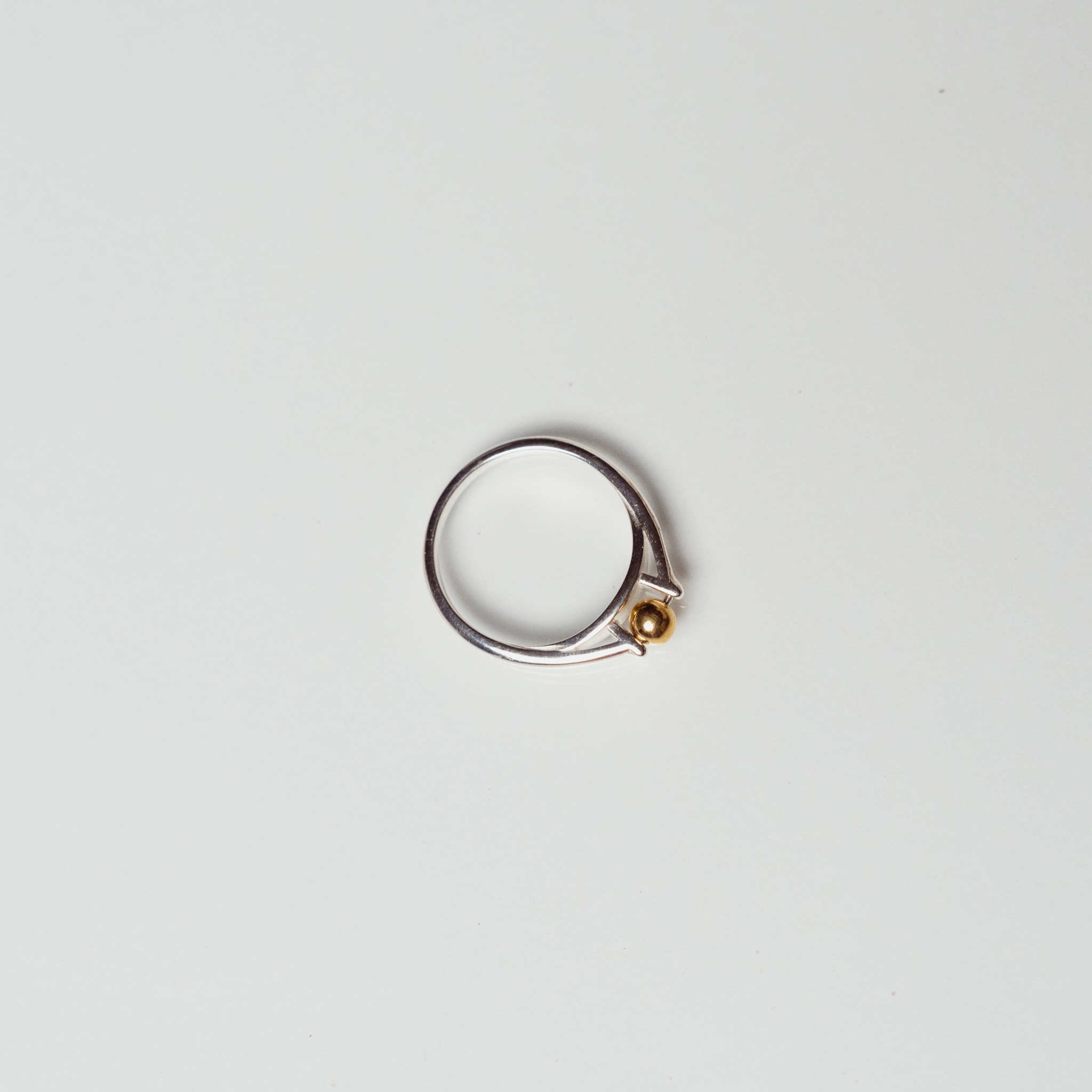 The India ring anxiety ring with silver band and mounted bronze ball on white background