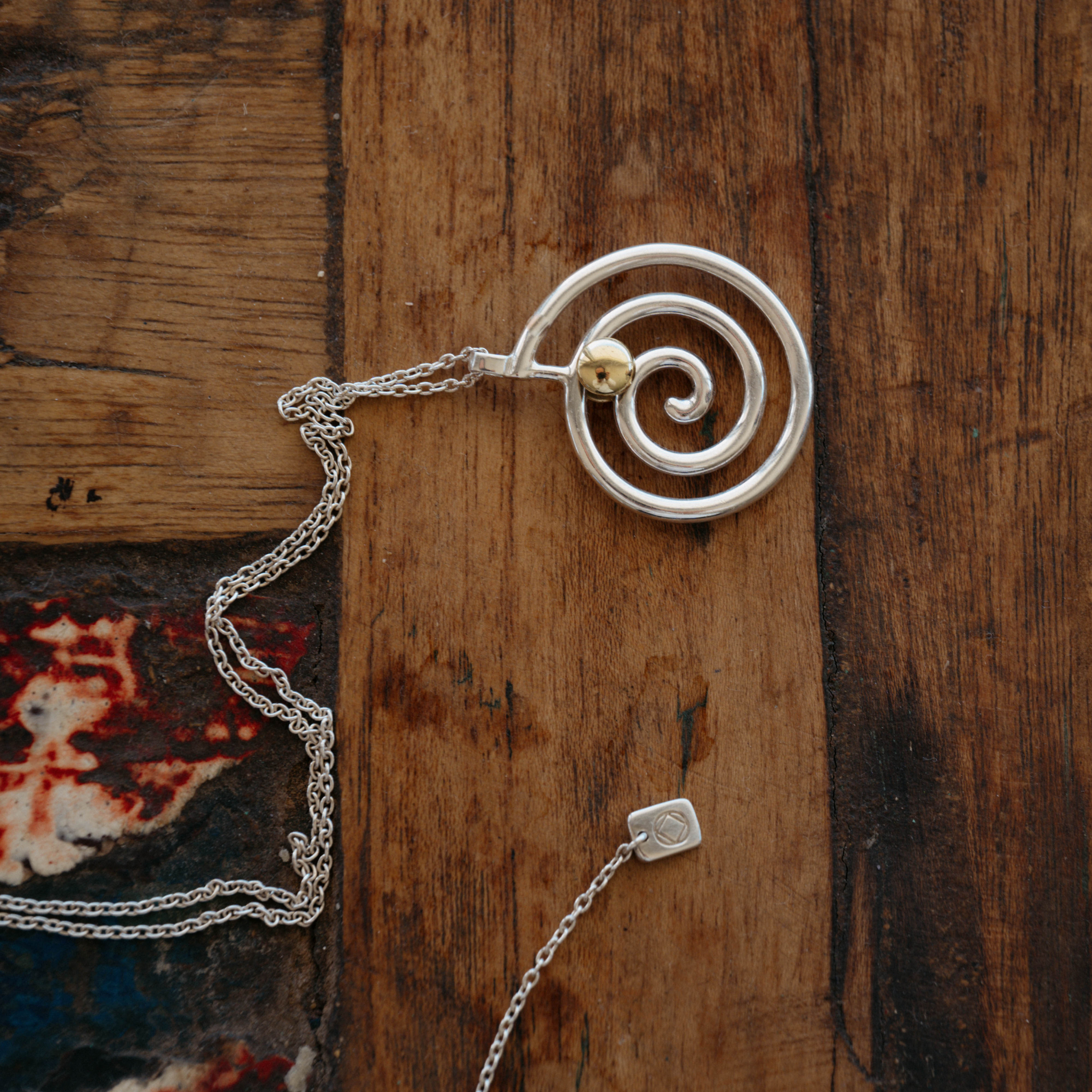 The Kirstie necklace anxiety necklace with silver spiral and bronze ball on wooden table