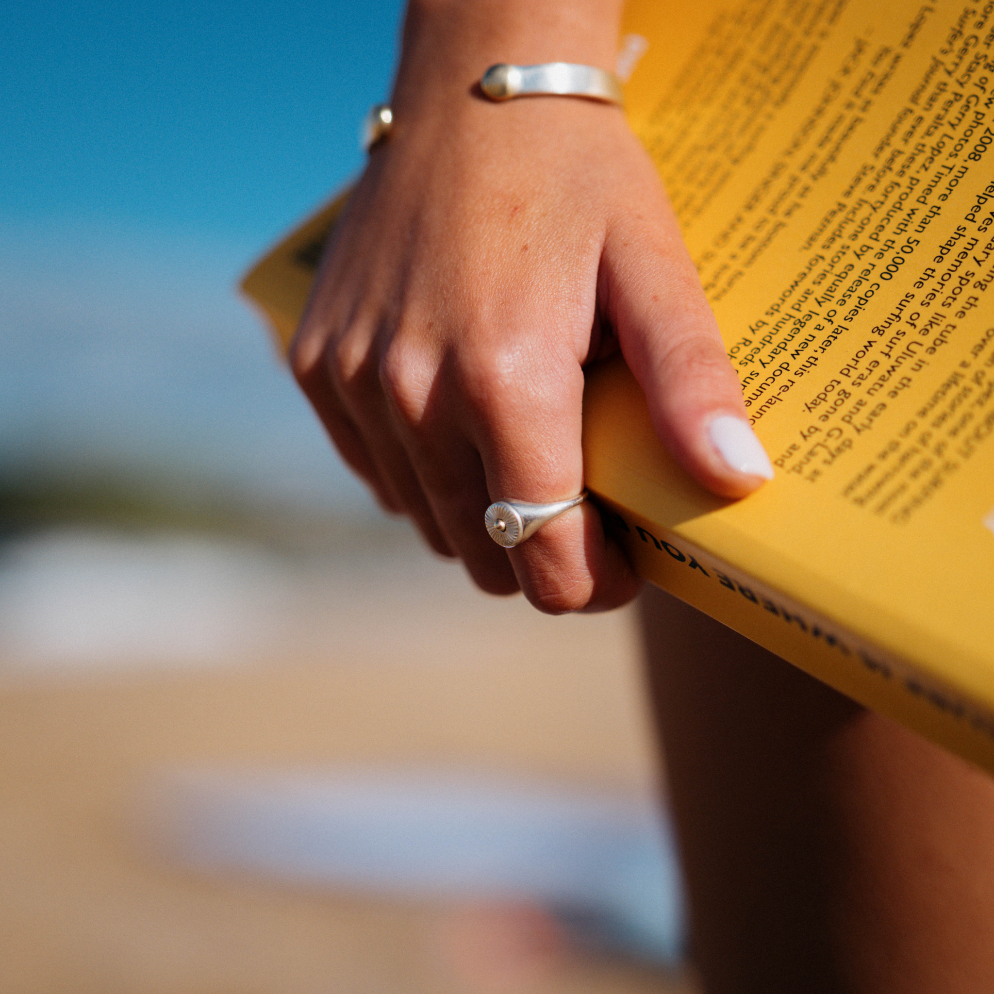 A white handing holding a book whilst wearing the Ellie ring from Star & co