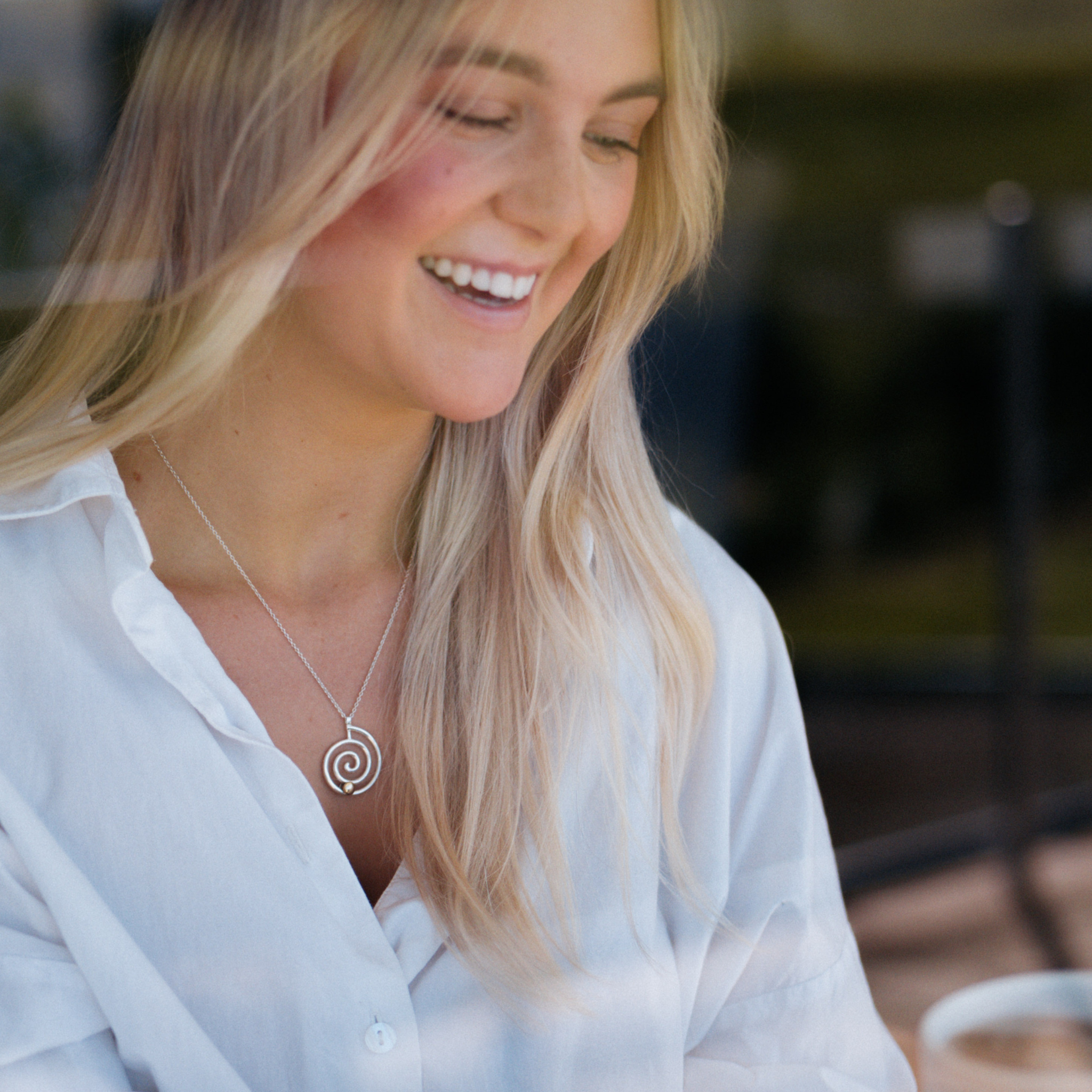 Girl laughing while wearing The Kirstie necklace anxiety necklace with silver spiral and bronze ball