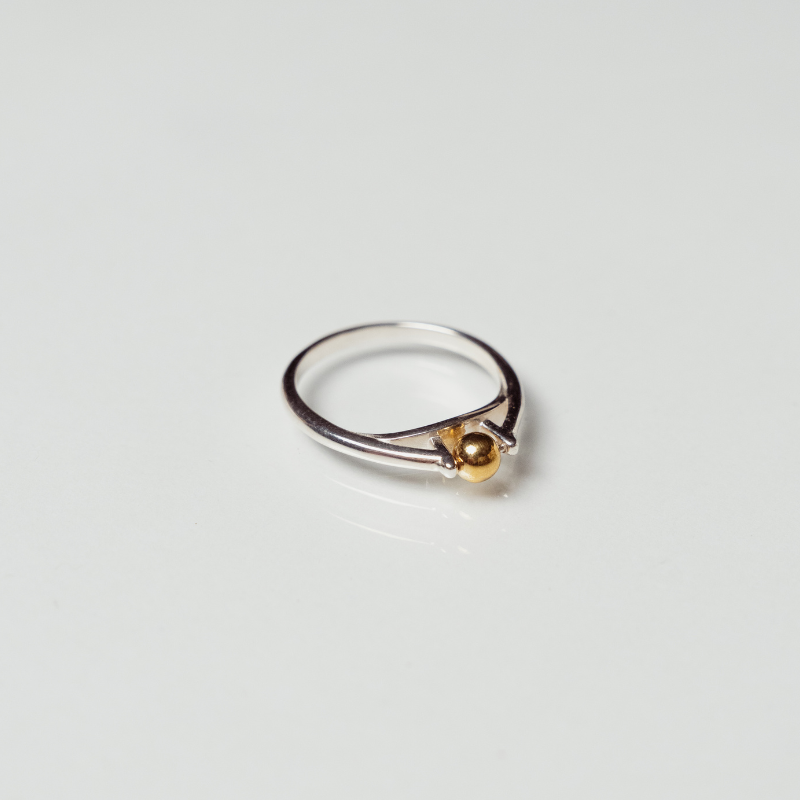 The India ring anxiety ring with silver band and mounted bronze ball on white background