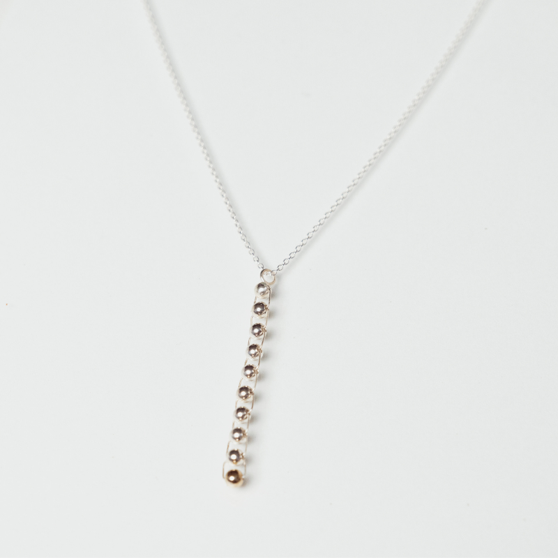 The Flor necklace anxiety necklace with silver and bronze balls mounted vertically on white background